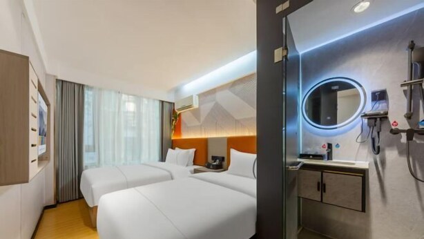 A hotel room with two beds, a bathroom with a mirror, and a small table. - YuanRui Hotel ( Financial City Keyun Road Subway Station Store) (Guangzhou)