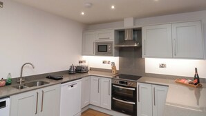 A modern kitchen with white cabinets, stainless steel appliances, and a built-in microwave.