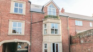 A red brick building with a garage entrance, a small balcony, and a window with a white frame.