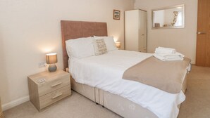 A bedroom with a bed, bedside tables, a wardrobe, and a mirror.