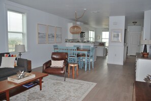 A spacious living room with a sofa, coffee table, and a dining area with chairs and a table. - Beachfront 3BR 3BA condo in the Pointe West Galveston community is beautiful! (Galveston)