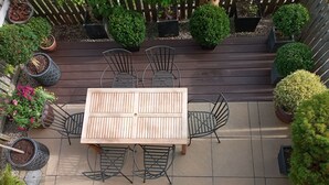 A wooden deck with a table and chairs, surrounded by potted plants and a wooden fence. - Great View, Parking, Sleeps 6, 3 bedrooms, 4 Beds, Easy walk to town (Stratford-upon-Avon)