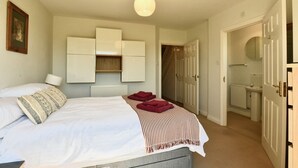 A bedroom with a bed, a radiator, a wardrobe, and a bathroom visible through an open door. - Great View, Parking, Sleeps 6, 3 bedrooms, 4 Beds, Easy walk to town (Stratford-upon-Avon)