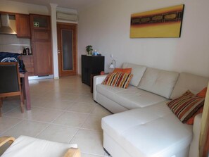 A living room with a sofa, a chair, a cabinet, and a painting on the wall.