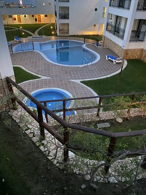 A rooftop pool area with a circular design, surrounded by a stone wall and a wooden fence.