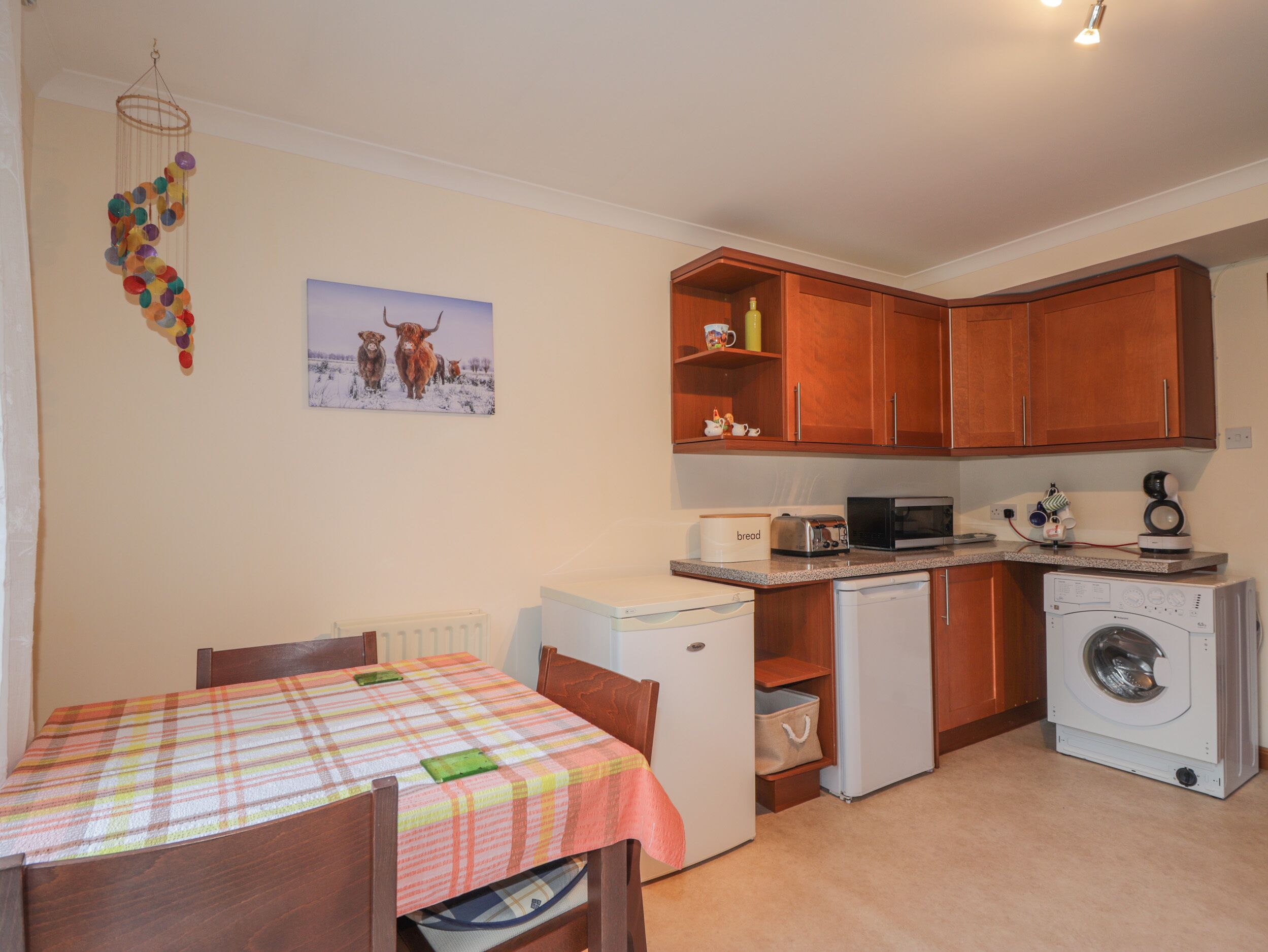 A compact kitchen with wooden cabinets, a microwave, a toaster, and a washing machine.