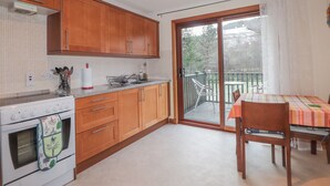 A kitchen with wooden cabinets, a white stove, and a dining area with a table and chairs. - Iola (Inverness)