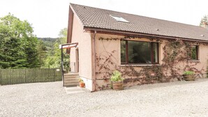 A single-story house with a tiled roof, a front porch, and a gravel driveway. - Iola (Inverness)