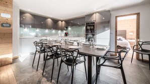 Une cuisine moderne avec des meubles de couleur sombre, un coin repas doté d’une table ronde et de chaises, ainsi qu’un four et un micro-ondes visibles.