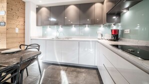 Une cuisine moderne avec des armoires blanches, un plan de travail en granit et une cuisinière intégrée.