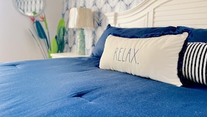 Ein Bett mit einer blauen Matratze und Kissen, wobei eines das Wort "RELAX" trägt.