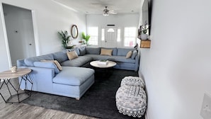Ein Wohnzimmer mit einem großen, L-förmigen Ecksofa, einem runden Couchtisch und einem kleinen Beistelltisch.