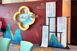 Uma área de recepção com painel decorativo, quadro de avisos e espaço de estar com cadeiras.