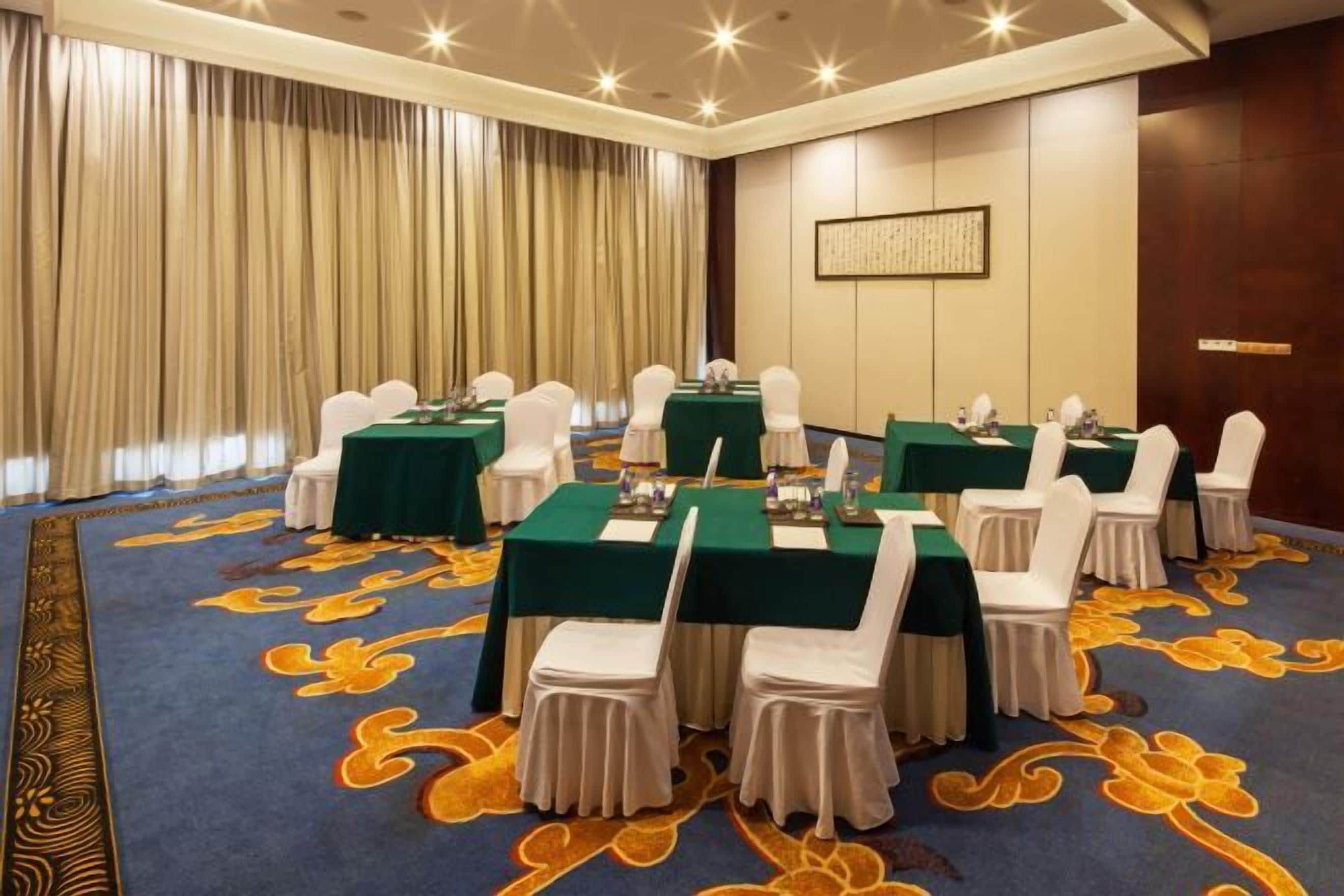 A conference room with tables and chairs, a patterned carpet, and a large window with curtains.