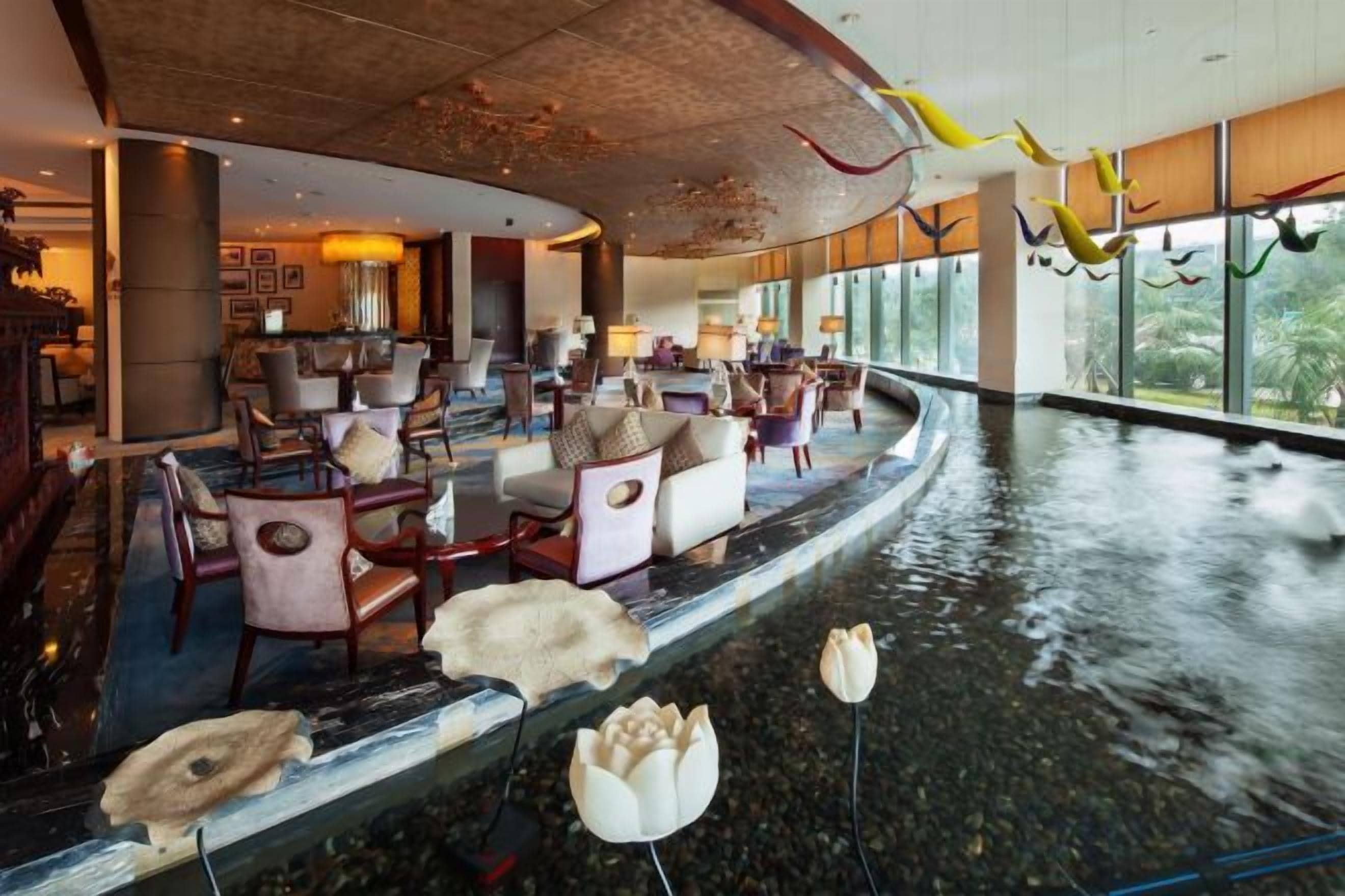 A spacious lobby with a curved ceiling, seating areas, and a water feature.