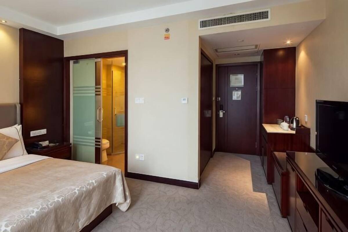 Habitación de hotel con cama, televisión, escritorio y baño.