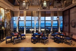 A hotel room with a large window, multiple tables and chairs, and a view of the cityscape. - Haizhongzhou International Hotel Apartment Building (Zhoushan)