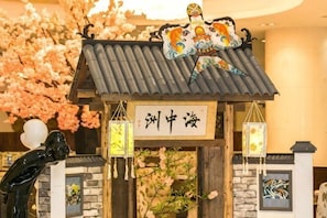 En traditionel japansk bygning med et tagdækket tag, en stenvæg og et skilt med japanske tegn.