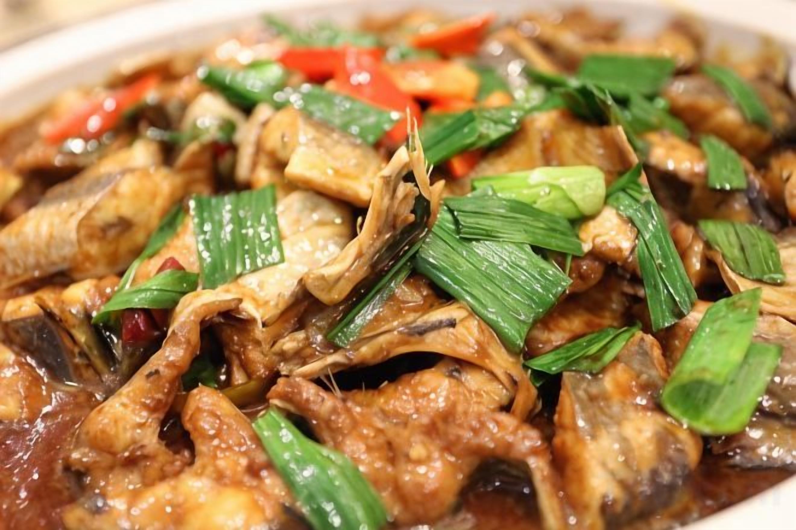 A dish with various ingredients, including meat and vegetables, garnished with green leaves.