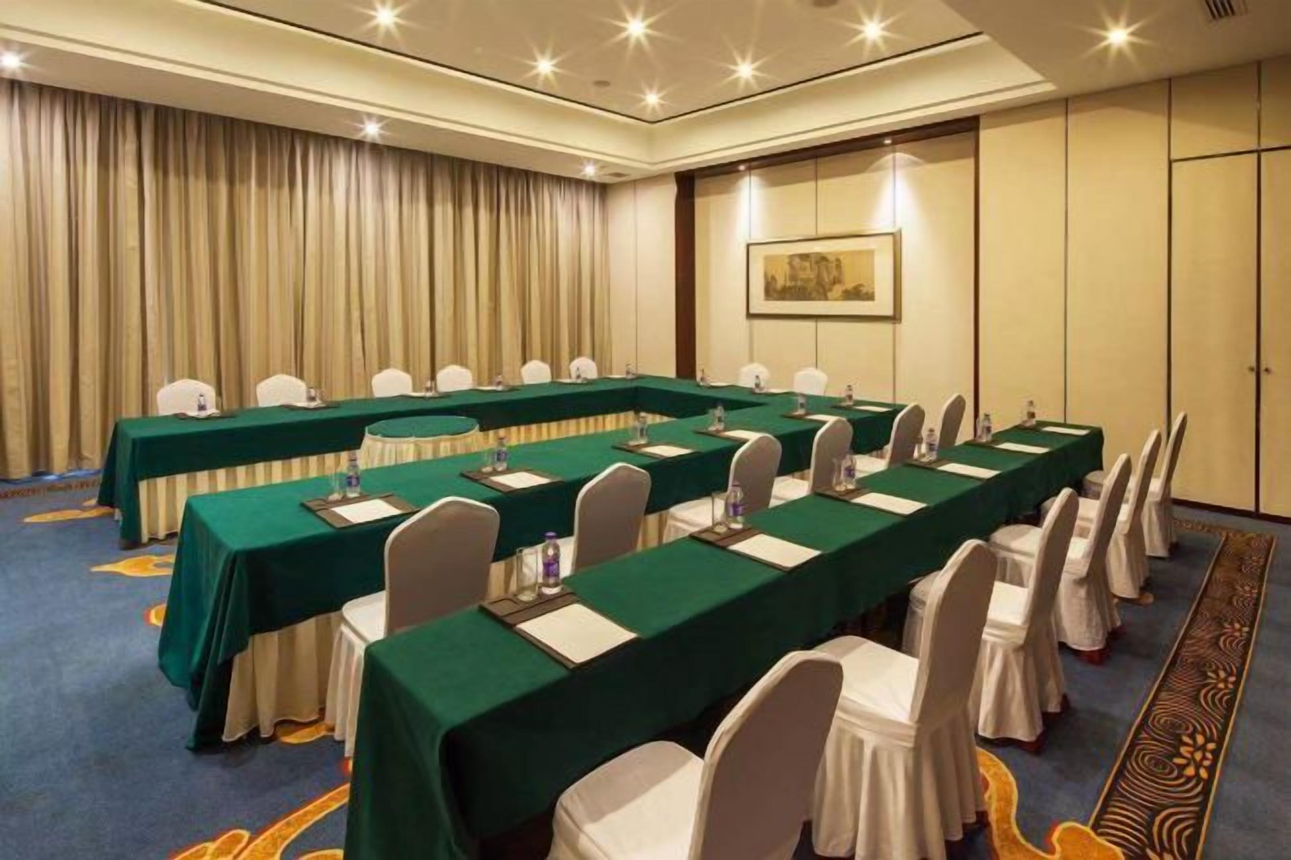 A conference room with long tables, chairs, and a carpeted floor.