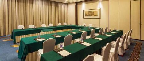 A conference room with long tables, chairs, and a carpeted floor.