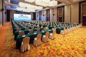 A conference room with rows of tables and chairs, a large screen at the front, and a carpeted floor. - Haizhongzhou International Hotel Apartment Building (Zhoushan)
