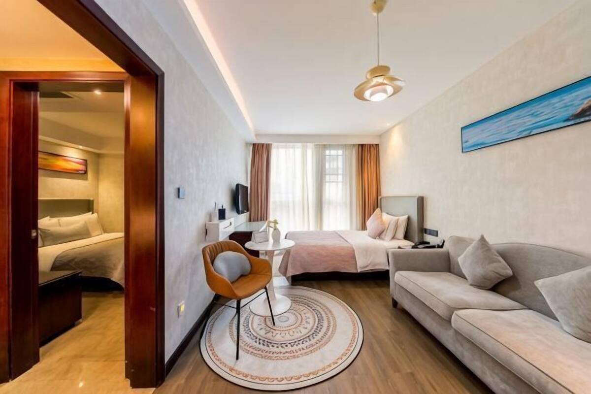 Una habitación de hotel moderna con cama, sofá, mesa de comedor y televisor.