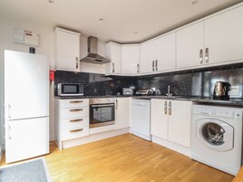Una cocina moderna con armarios blancos, microondas, horno, tostadora y lavadora.