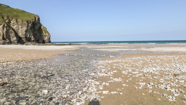 Une plage avec un terrain rocheux et une falaise.