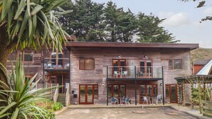 Un bâtiment en bois à deux étages, doté d’un balcon, d’un espace extérieur aménagé pour s’asseoir et d’un jardin.