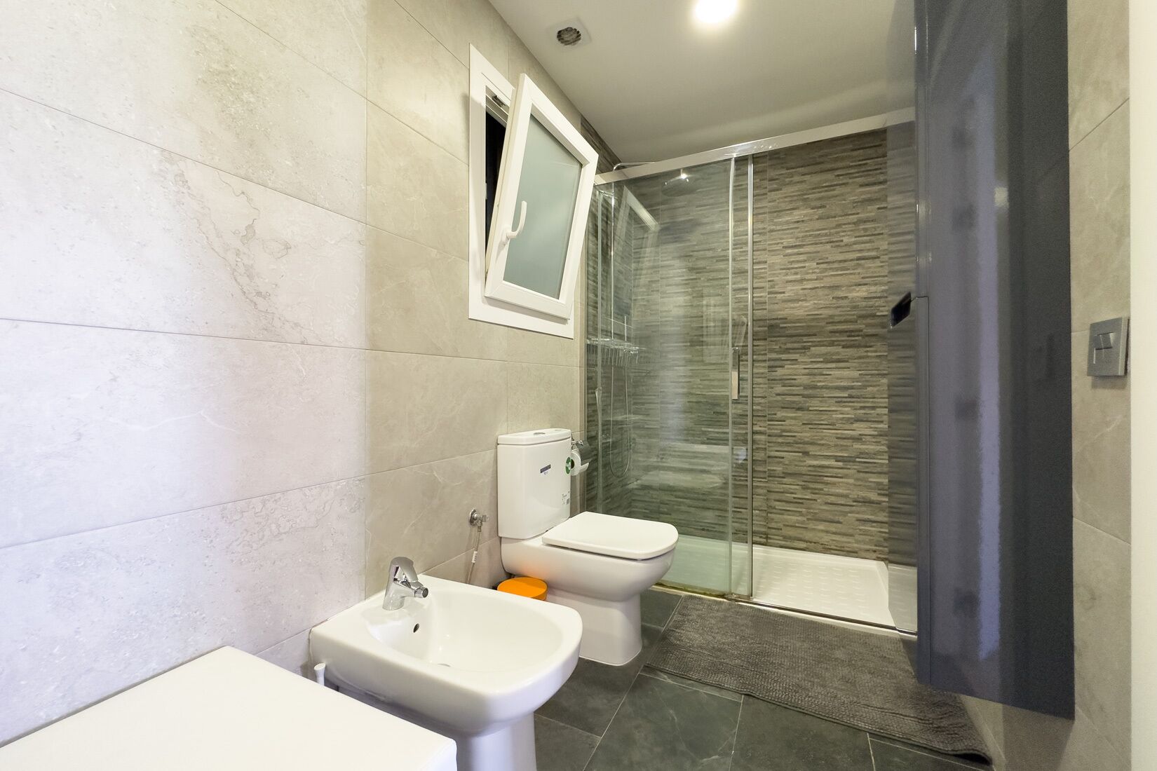 Een moderne badkamer met toilet, bidet en douchecabine.