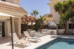 A poolside area with lounge chairs, a barbecue grill, and a pergola. - Protaras Villa Athamas Blue (Protaras)