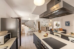 A modern kitchen with a large island, a built-in oven, and a stainless steel refrigerator. - Protaras Villa Athamas Blue (Protaras)
