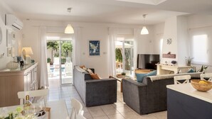 A modern living room with a sofa, dining table, and TV. - Protaras Villa Athamas Blue (Protaras)