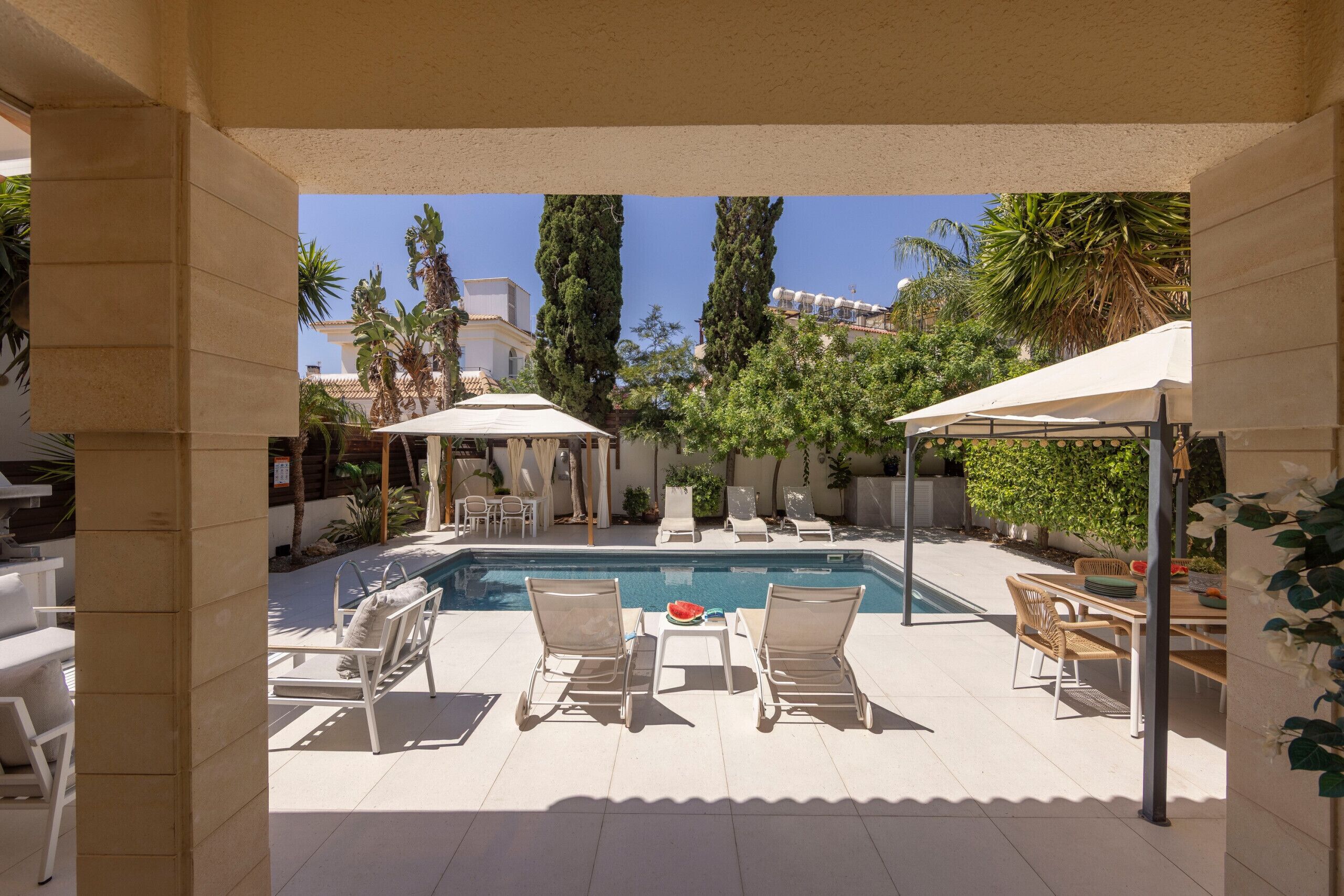 A pool area with lounge chairs, a table, and umbrellas.