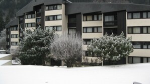 Een meerlaags gebouw met een plat dak en een symmetrische gevel, omgeven door besneeuwde grond en bomen.