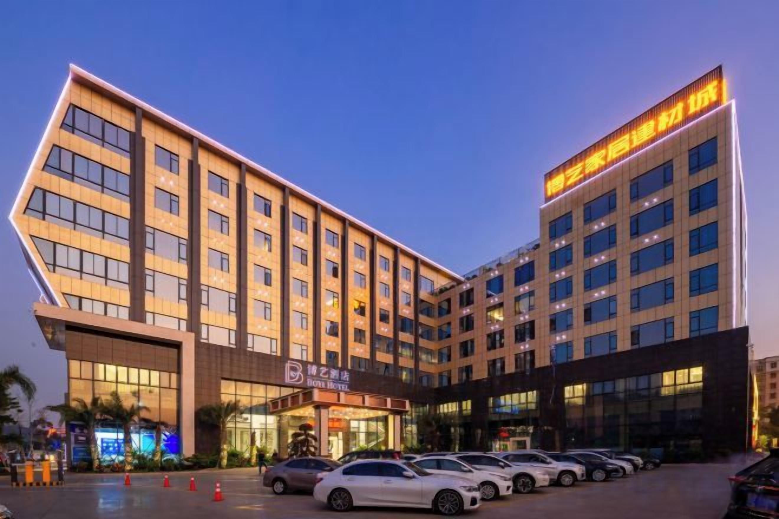 A modern hotel with multiple floors, a parking lot, and a prominent entrance.