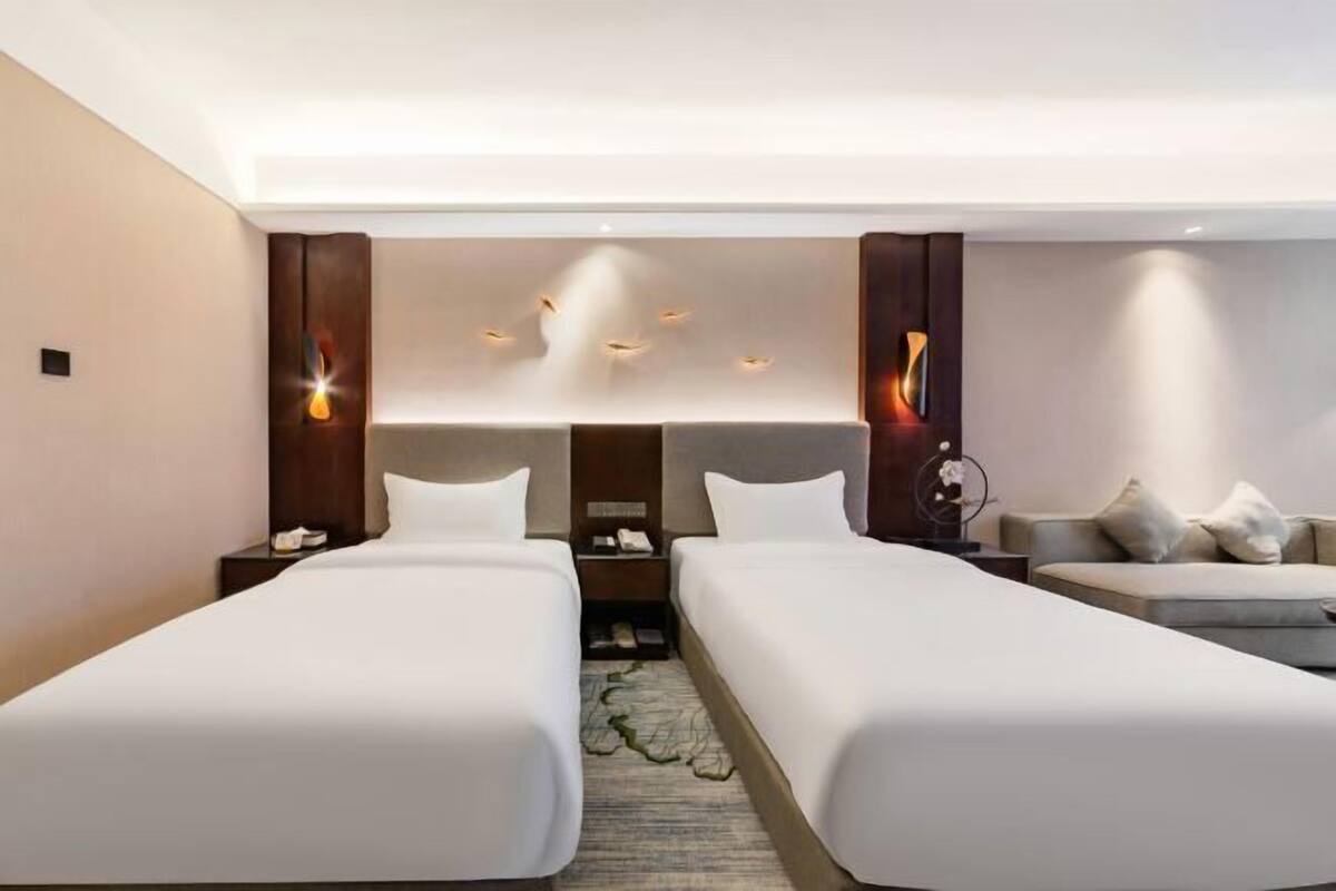 Une chambre d’hôtel moderne avec deux lits simples, un canapé et une petite table.