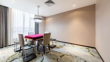 A hotel room with a dining table, chairs, a red tablecloth, a ceiling light, and a patterned carpet.