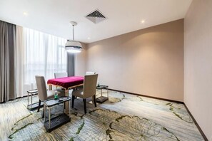 A hotel room with a dining table, chairs, a red tablecloth, a ceiling light, and a patterned carpet. - Boyi Hotel (Foshan)