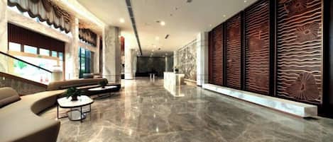 A spacious lobby with a marble floor, seating area, and a reception desk.