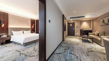A hotel room with a large bed, a desk, a sofa, and a carpet with a leaf pattern.