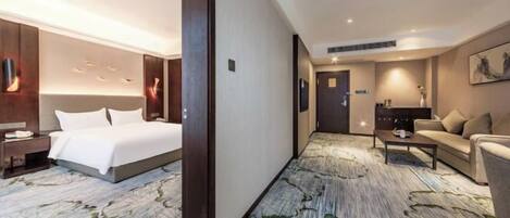 A hotel room with a large bed, a desk, a sofa, and a carpet with a leaf pattern.