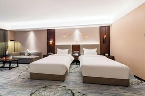 A hotel room with two beds, a sofa, a coffee table, and a lamp. - Boyi Hotel (Foshan)
