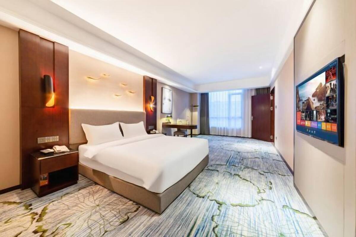 Une chambre d’hôtel avec un grand lit, un bureau, une chaise et un téléviseur.