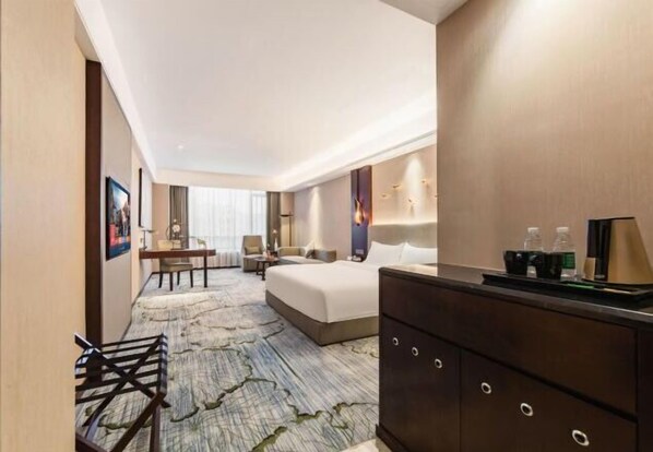 A hotel room with a bed, a desk, a chair, a dresser, and a large window. - Boyi Hotel (Foshan)