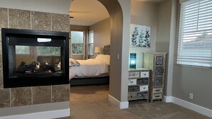 Un dormitorio con chimenea, cama, mesita de noche y cómoda.