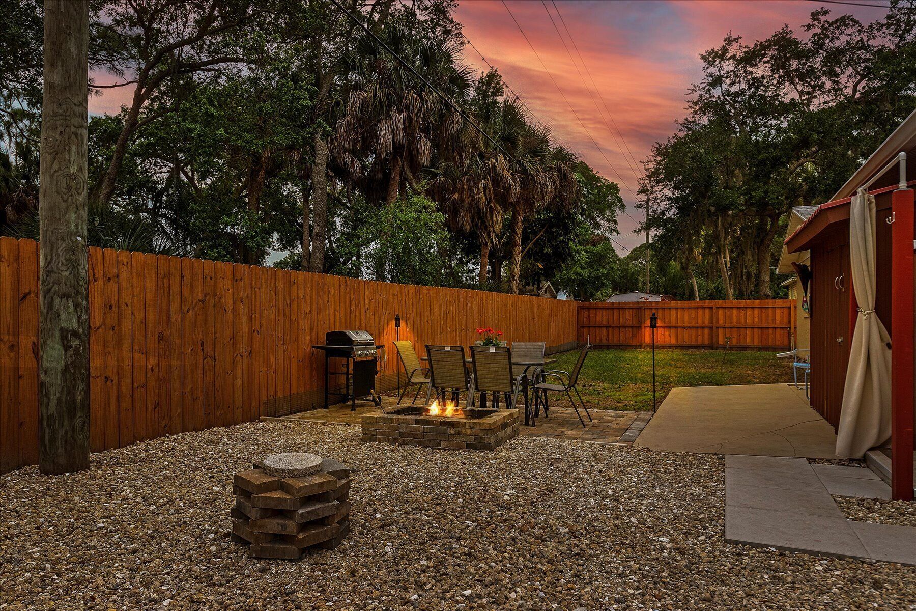 A backyard with a fire pit, outdoor furniture, and a wooden fence.