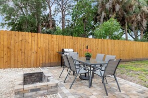Enjoy al fresco dining on the patio, surrounded by lush greenery and a fire pit.