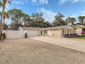 Ein Bungalow mit Garage, überdachter Auffahrt und Zuwegung mit Kies.